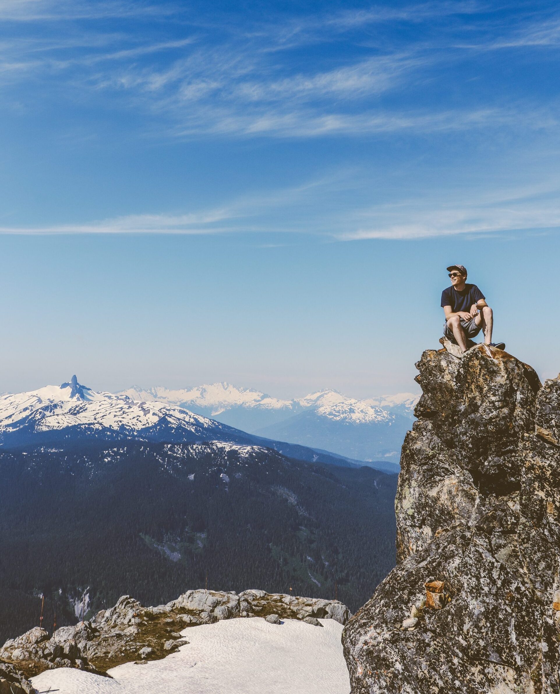 Tom Carless, Founder of AB Split Test sits on a rocky ledge overlooking Black Tusk, Whistler, BC under a clear blue sky.
